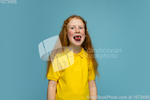 Image of Happy redhair girl isolated on blue studio background. Looks happy, cheerful, sincere. Copyspace. Childhood, education, emotions concept