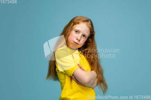 Image of Happy redhair girl isolated on blue studio background. Looks happy, cheerful, sincere. Copyspace. Childhood, education, emotions concept