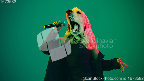 Image of Talented dog, professional musician performing on green background in neon light. Concept of music, hobby, festival, contemporary art collage. Modern design.