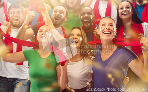 Image of Italian football, soccer fans cheering their team with a red scarfs at stadium. Excited fans cheering a goal, supporting favourite players