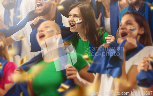 Image of Uruguayan football, soccer fans cheering their team with a blue scarfs at stadium. Excited fans cheering a goal, supporting favourite players