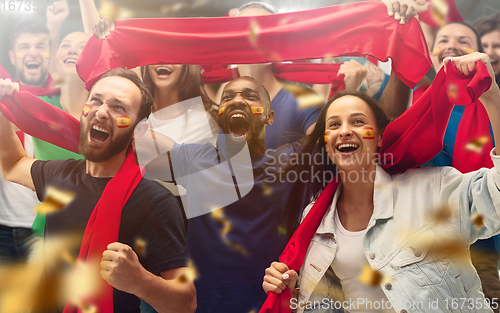 Image of Spainian football, soccer fans cheering their team with a red scarfs at stadium. Excited fans cheering a goal, supporting favourite players