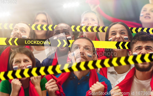 Image of Netherlands soccer fans cheering for favourite sport team with bright emotions, excited, wondered behind the limiting tapes with Lockdown