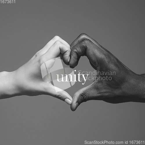 Image of African and caucasian hands gesturing on gray studio background, tolerance and equality concept