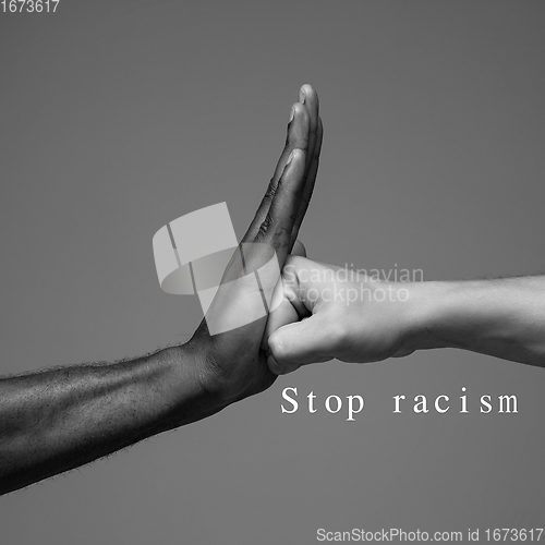 Image of African and caucasian hands gesturing on gray studio background, tolerance and equality concept