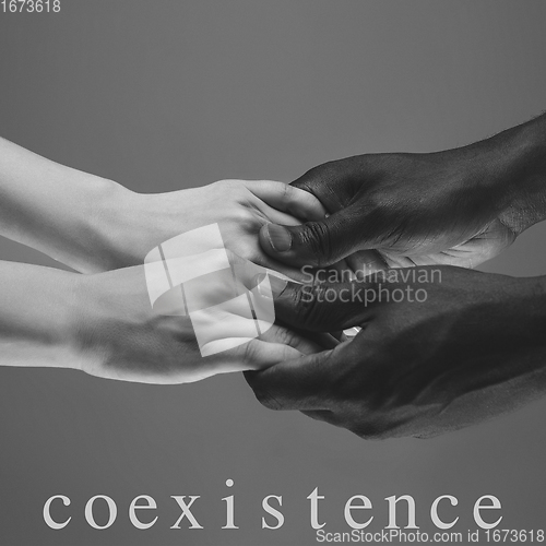 Image of African and caucasian hands gesturing on gray studio background, tolerance and equality concept