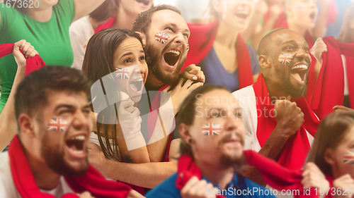 Image of Britainian football, soccer fans cheering their team with a red scarfs at stadium. Excited fans cheering a goal, supporting favourite players