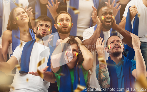 Image of Belgian football, soccer fans cheering their team with a blue scarfs at stadium. Excited fans cheering a goal, supporting favourite players