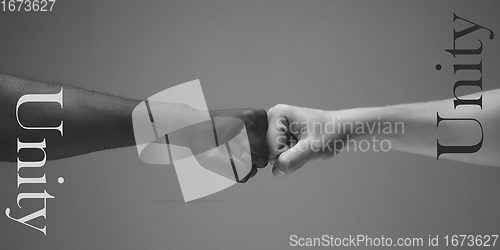 Image of African and caucasian hands gesturing on gray studio background, tolerance and equality concept. Unity.