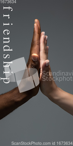 Image of African and caucasian hands gesturing on gray studio background, tolerance and equality concept