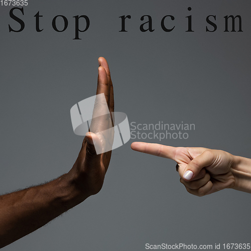 Image of African and caucasian hands gesturing on gray studio background, tolerance and equality concept