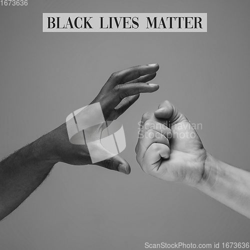 Image of African and caucasian hands gesturing on gray studio background, tolerance and equality concept