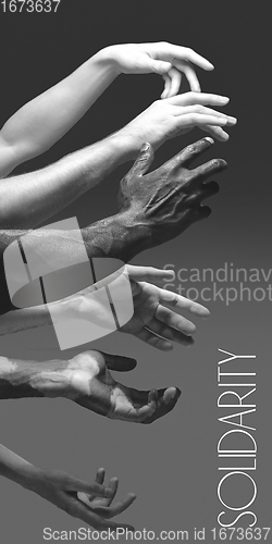 Image of African and caucasian hands gesturing on gray studio background, tolerance and equality concept
