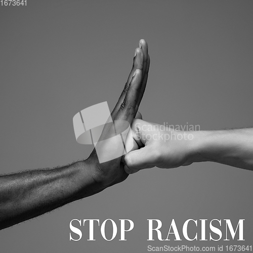 Image of African and caucasian hands gesturing on gray studio background, tolerance and equality concept