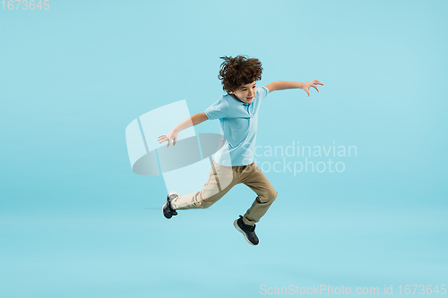 Image of Childhood and dream about big and famous future. Pretty little boy isolated on blue background