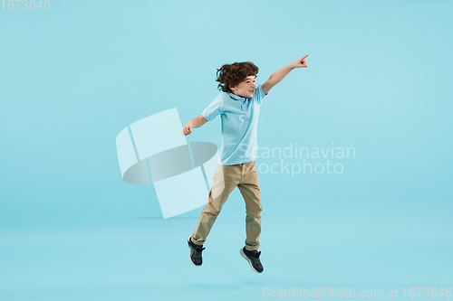 Image of Childhood and dream about big and famous future. Pretty little boy isolated on blue background