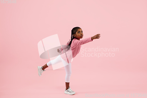 Image of Childhood and dream about big and famous future. Pretty little girl isolated on coral pink background