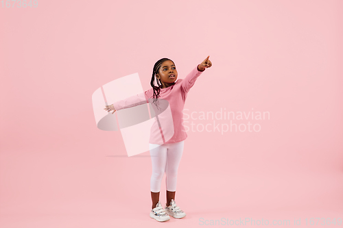 Image of Childhood and dream about big and famous future. Pretty little girl isolated on coral pink background