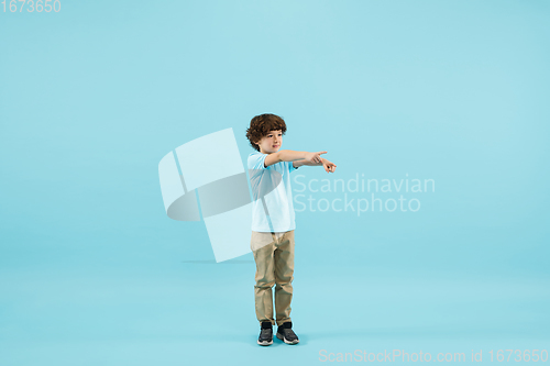 Image of Childhood and dream about big and famous future. Pretty little boy isolated on blue background