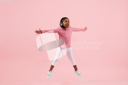 Image of Childhood and dream about big and famous future. Pretty little girl isolated on coral pink background