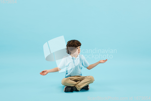 Image of Childhood and dream about big and famous future. Pretty little boy isolated on blue background