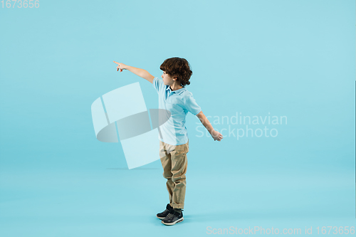 Image of Childhood and dream about big and famous future. Pretty little boy isolated on blue background