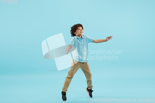 Image of Childhood and dream about big and famous future. Pretty little boy isolated on blue background