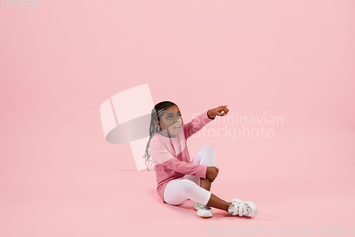 Image of Childhood and dream about big and famous future. Pretty little girl isolated on coral pink background