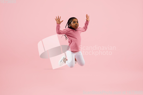 Image of Childhood and dream about big and famous future. Pretty little girl isolated on coral pink background