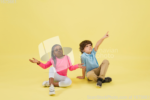 Image of Childhood and dream about big and famous future. Pretty little kids isolated on yellow background