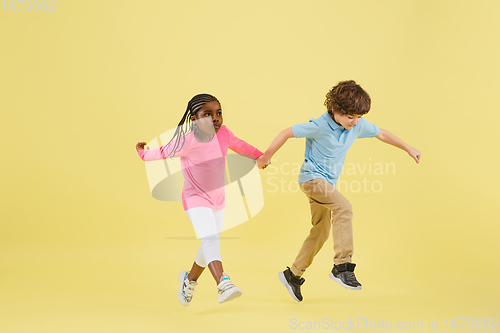 Image of Childhood and dream about big and famous future. Pretty little kids isolated on yellow background