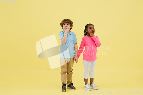 Image of Childhood and dream about big and famous future. Pretty little kids isolated on yellow background