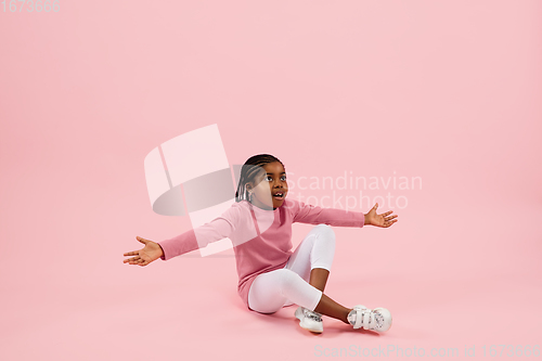 Image of Childhood and dream about big and famous future. Pretty little girl isolated on coral pink background