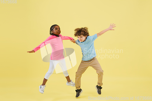 Image of Childhood and dream about big and famous future. Pretty little kids isolated on yellow background