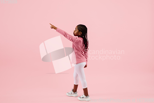 Image of Childhood and dream about big and famous future. Pretty little girl isolated on coral pink background