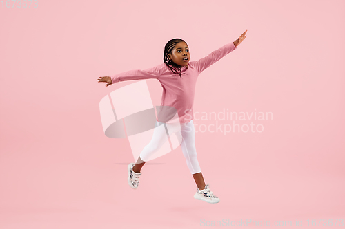 Image of Childhood and dream about big and famous future. Pretty little girl isolated on coral pink background