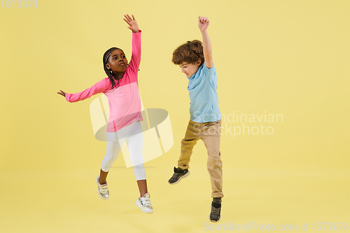 Image of Childhood and dream about big and famous future. Pretty little kids isolated on yellow background