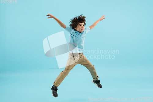 Image of Childhood and dream about big and famous future. Pretty little boy isolated on blue background