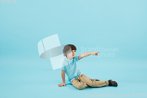 Image of Childhood and dream about big and famous future. Pretty little boy isolated on blue background