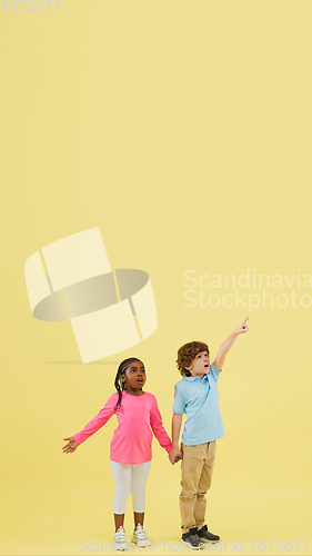 Image of Childhood and dream about big and famous future. Pretty little kids isolated on yellow background