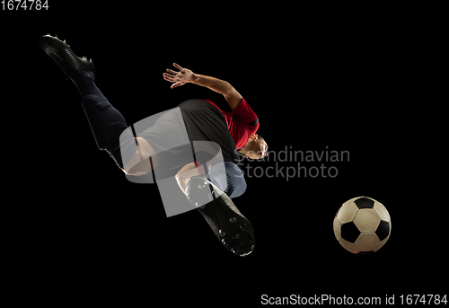 Image of Young caucasian football, soccer player in action, motion isolated on black background, look from the bottom. Concept of sport, movement, energy and dynamic.