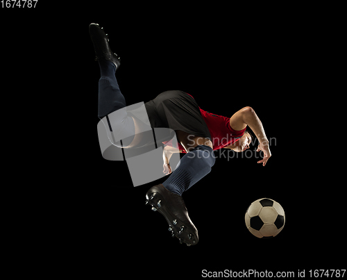 Image of Young caucasian football, soccer player in action, motion isolated on black background, look from the bottom. Concept of sport, movement, energy and dynamic.
