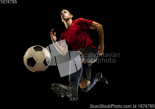 Image of Young caucasian football, soccer player in action, motion isolated on black background, look from the bottom. Concept of sport, movement, energy and dynamic.