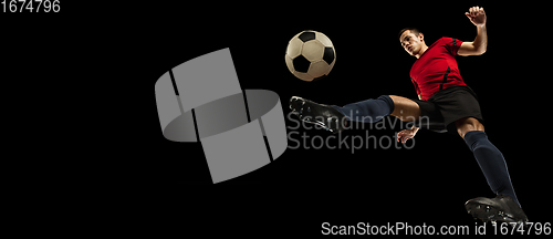 Image of Young caucasian football, soccer player in action, motion isolated on black background, look from the bottom. Concept of sport, movement, energy and dynamic.