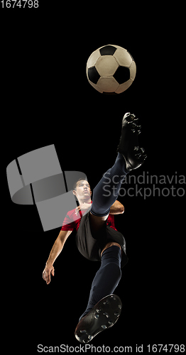 Image of Young caucasian football, soccer player in action, motion isolated on black background, look from the bottom. Concept of sport, movement, energy and dynamic.