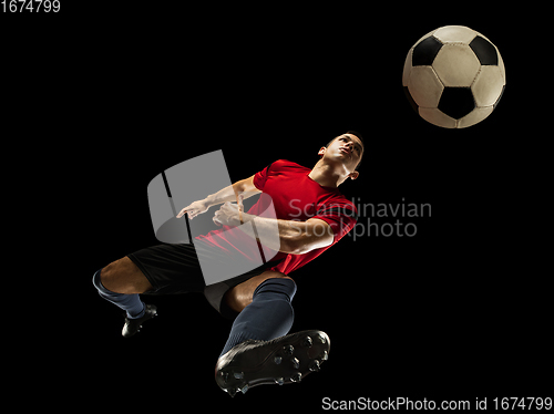 Image of Young caucasian football, soccer player in action, motion isolated on black background, look from the bottom. Concept of sport, movement, energy and dynamic.