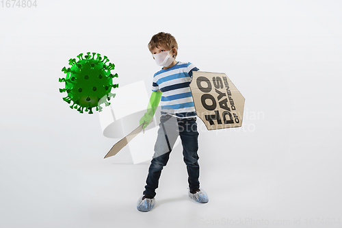 Image of Little caucasian boy as a warrior in fight with coronavirus pandemic, with a shield, a sword and a toilet paper bandoleer.