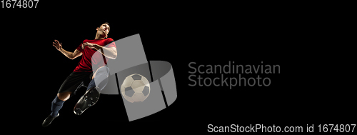 Image of Young caucasian football, soccer player in action, motion isolated on black background, look from the bottom. Concept of sport, movement, energy and dynamic.