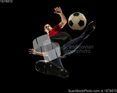 Image of Young caucasian football, soccer player in action, motion isolated on black background, look from the bottom. Concept of sport, movement, energy and dynamic.