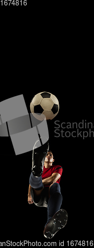 Image of Young caucasian football, soccer player in action, motion isolated on black background, look from the bottom. Concept of sport, movement, energy and dynamic.
